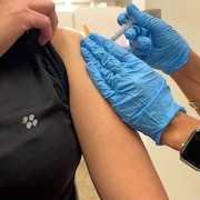 Une femme reçoit une dose de vaccin dans une épaule.