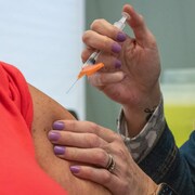 Une infirmière s'apprête à administrer un vaccin à une femme.
