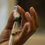 Gros plan sur la main d'une femme en train de préparer un vaccin.
