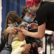 Corey Herscu tient sa fille Noa, 6 ans, qui se fait vacciner.