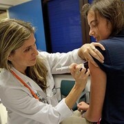 Une infirmière vaccine une jeune fille dans le bras. 