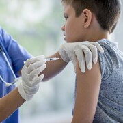 Un jeune garçon d'environ 7 ans se fait vacciner par une infirmière.