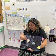 L'enseignante en classe d'accueil Vanessa Ibanez montre aux enfants un livre sur le système solaire. 