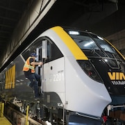 Un employé montant dans la locomotive d'un train de Via Rail Canada.