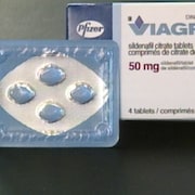 Gros plan sur quatre pilules et une boite de Viagra. 