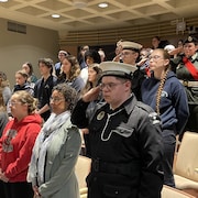 Des élèves qui font un salut et chantent l'hymne nationale du Canada pendant la cérémonie de commémoration de la victoire des Alliés à Sudbury.