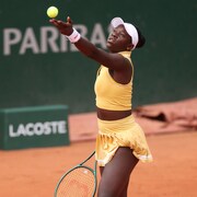 Victoria Mboko s'apprête à servir et lance la balle de tennis jaune