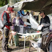 Trois personnes en train de regarder des choses sur une table dehors, au parc Crab, à Vancouver, en octobre 2023.