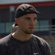 Un jeune homme porte une casquette à l'envers sur le terrain de football du PEPS de l'Université Laval. 