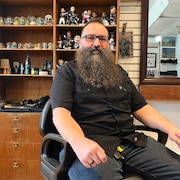 Vincent Lavallée porte une grosse barbe. Il est assis dans un fauteuil de barbier.