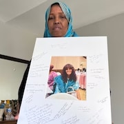 Une femme tient une affiche avec la photo de sa fille qui a été victime d'un féminicide.