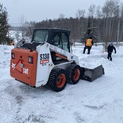 Deux hommes s'affairent à décontaminer la neige et le sol sur un terrain privé.