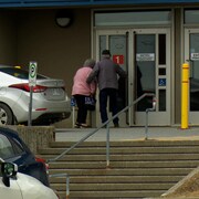Un homme qui assiste une femme afin d'entrer à l'intérieur de l'hôpital.