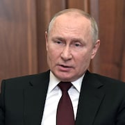 Portrait de Vladimir Poutine assis à un bureau.