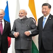 Le Premier ministre indien Narendra Modi, tenant la main du président russe Vladimir Poutine et du chef de l'État chinois Xi Jinping, lors du sommet du G20 de 2019 au Japon.