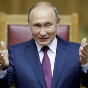 Le président russe Vladimir Poutine gesticule assis dans un fauteuil. 
