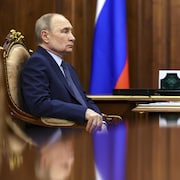 Vladimir Poutine est assis.