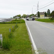Un véhicule de la Sûreté du Québec barre une rue résidentielle le long du fleuve.