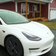 Une voiture Tesla garée devant une maison.