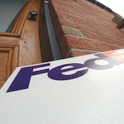 Boîte FedEx laissée sur le pas d'une porte.