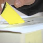 Une main place un bulletin dans une urne électorale.