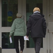 Deux électrices, munies d'une carte de vote, se dirigent vers l'entrée d'un bureau de scrutin à Toronto.