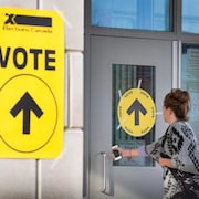 Une femme entre dans un endroit pour voter.