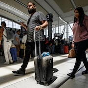 Des voyageurs avec leur valise à l'aéroport Pearson.