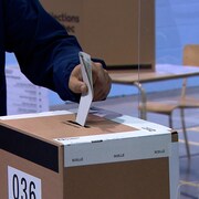 Un citoyen dépose son bulletin de vote dans une boîte.