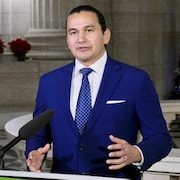 Le premier ministre du Manitoba, Wab Kinew, parle au micro d'un podium au Palais législatif du Manitoba.