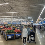 Des personnes magasinent dans le rayon des fruits et légumes au Walmart.