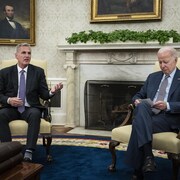 Deux hommes assis sur des fauteuils devant une cheminée.