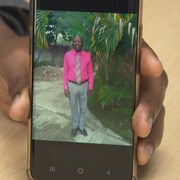 Un homme montre une photo de son frère sur son téléphone. 