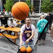 Une personne portant un chandail des Lakers lance des ballons de basketball.