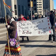 Des manifestants portant une affiche à Winnipeg, le 7 avril 2023.