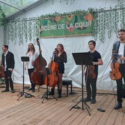 Les six membres de la formation Wooden Shape sont debout sur une scène et tiennent leur instrument de musique dans leurs mains. 