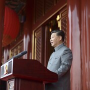 Xi Jinping derrière un micro regardant droit devant