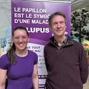 Une femme et un homme se tiennent debout devant une affiche du lupus.