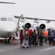 Des personnes en train d'embarquer dans un avion à Yellowknife, le 19 août 2023.