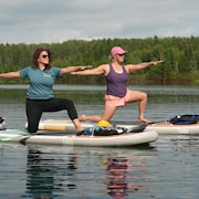 Deux femmes font un mouvement synchronisé de yoga sur leur planche à pagaie.