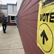 Un électeur se dirige vers l'entrée d'un lieu de scrutin marqué par des affiches.