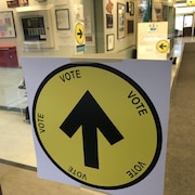 Une affiche indiquant un bureau de vote dans un couloir d'école.