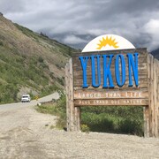 Enseigne montrant la frontière du Yukon avec un véhicule qui passe sur la route.