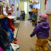 Un enfant court dans un couloir vers d'autres enfants.