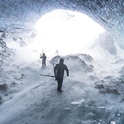 Deux personnes sont dans un tunnel de glace. Ils marchent vers la lumière.
