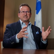 Yves-François Blanchet en entrevue devant un drapeau du Québec.