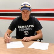 Bolduc signe un contrat avec une casquette des Blues sur la tête. 