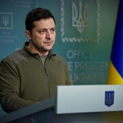 Le président de l'Ukraine, Volodymyr Zelensky, debout derrière un lutrin.