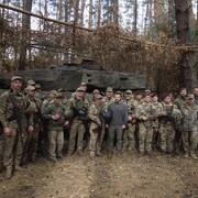 Volodymyr Zelensky pose devant un tank, entouré de soldats.