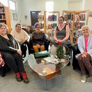 Cinq femmes assises dans une bibliothèque.